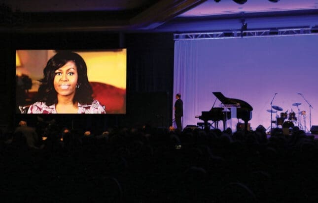 A woman's face projected on screen in front of an audience