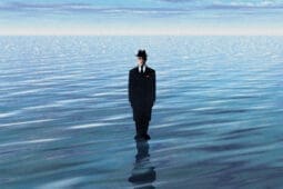 A man in a suit stands in a body of water