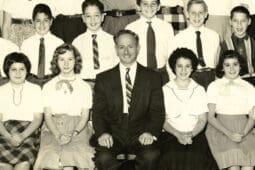 A black and white class photo with an American flag backdrop