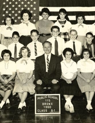 A black and white class photo with an American flag backdrop