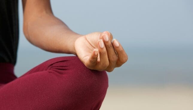 A person holds their hand in a meditative pose