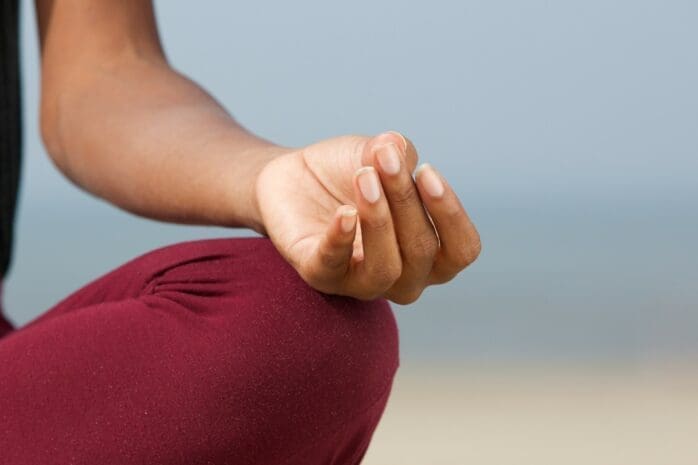 A person holds their hand in a meditative pose