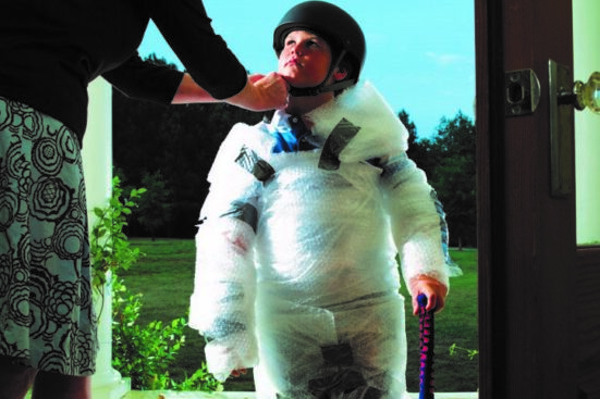 A parent wrapping their child in bubble wrap and helmet