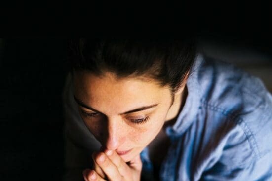 A woman holds her hands to her mouth contemplatively