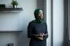 Black woman with a head scarf stares out the window - Photo Credit: Pexels/Monstera