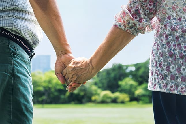 Older couple holding hands | Photo by iStock/RAWPIXEL