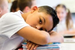 A young boy with his head on his desk | iStock/DG Images