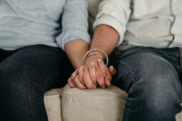 Two people holding hands on a couch | Photo by Ketut Subiyanto/Pexels