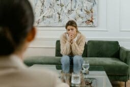 a sad woman sitting on a couch in front of her therapist | Photo by Mart Production/Pexels