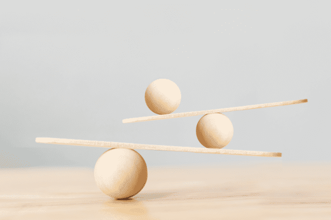 Three wooden balls balancing on wooden boards on a table.