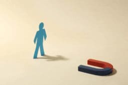 A cutout of a figure stands near a horseshoe-shaped magnet pointed at it