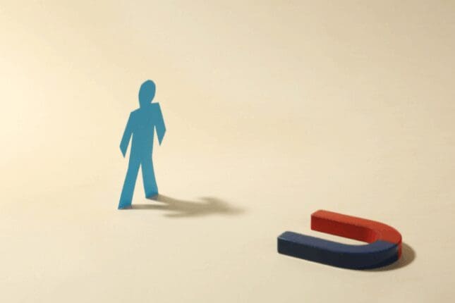 A cutout of a figure stands near a horseshoe-shaped magnet pointed at it