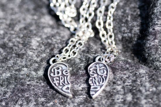 A two-piece friendship necklace rests on a stone backdrop