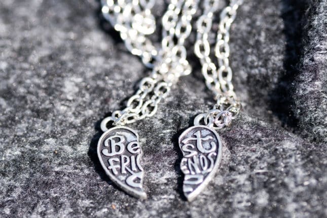 A two-piece friendship necklace rests on a stone backdrop