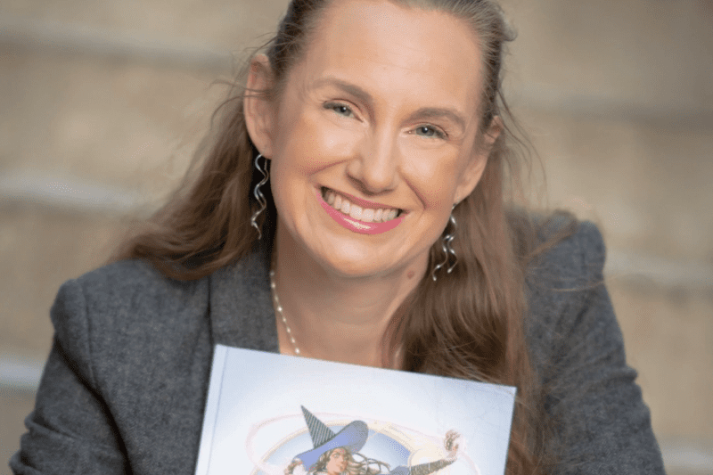 Megan Connell holding a D&D book and smiling to camera
